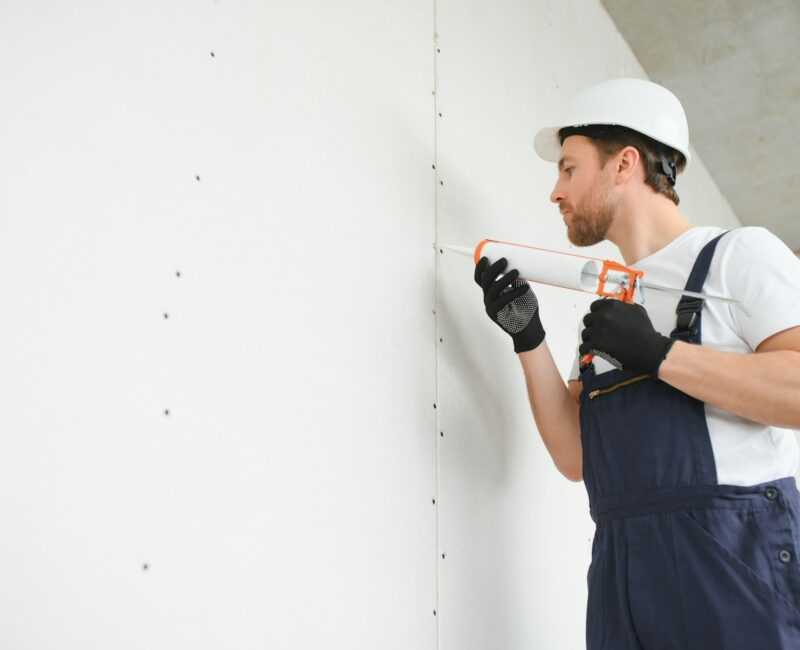 Professional Workman Applying Silicone Sealant With Caulking Gun on the Wall