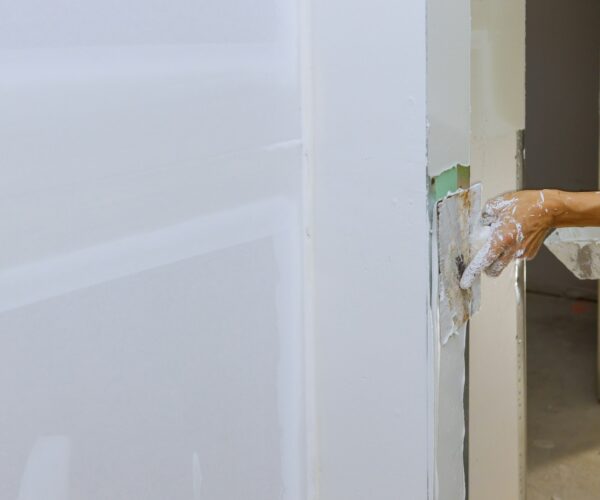 Worker spreading coating plaster the walls with putty